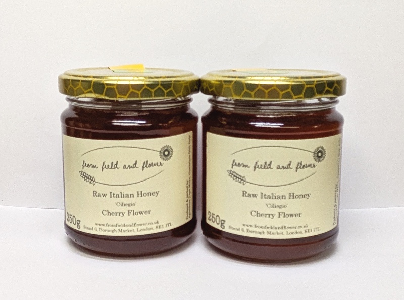 2 jars of cherry flower honey, next to each other on a white background