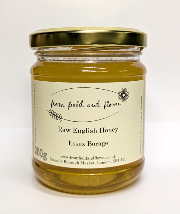 Glass jar of borage honey on white background.